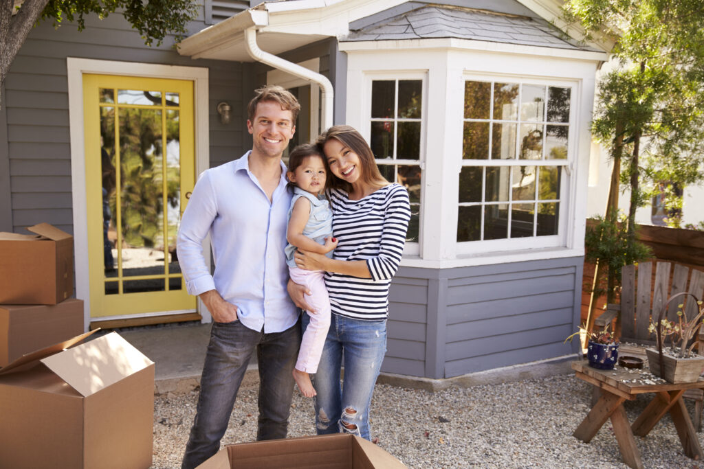 Family with daughter in front of house with boxes