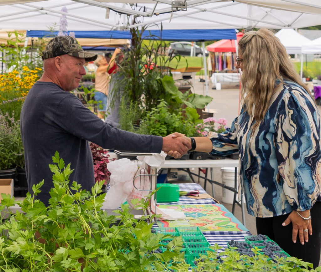 Two people shaking hands at a farmers' market