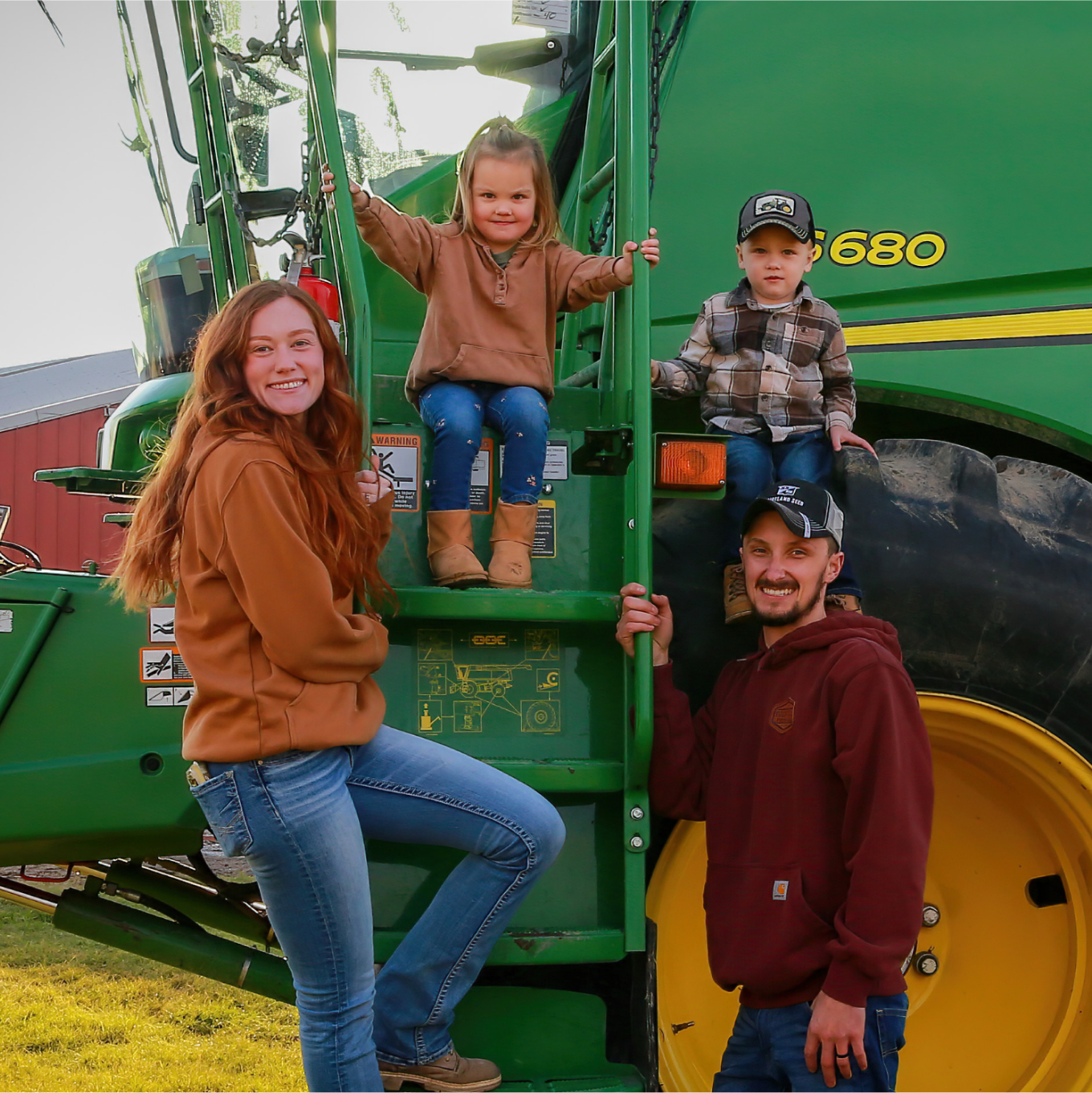 A smiling family on and around a harvester