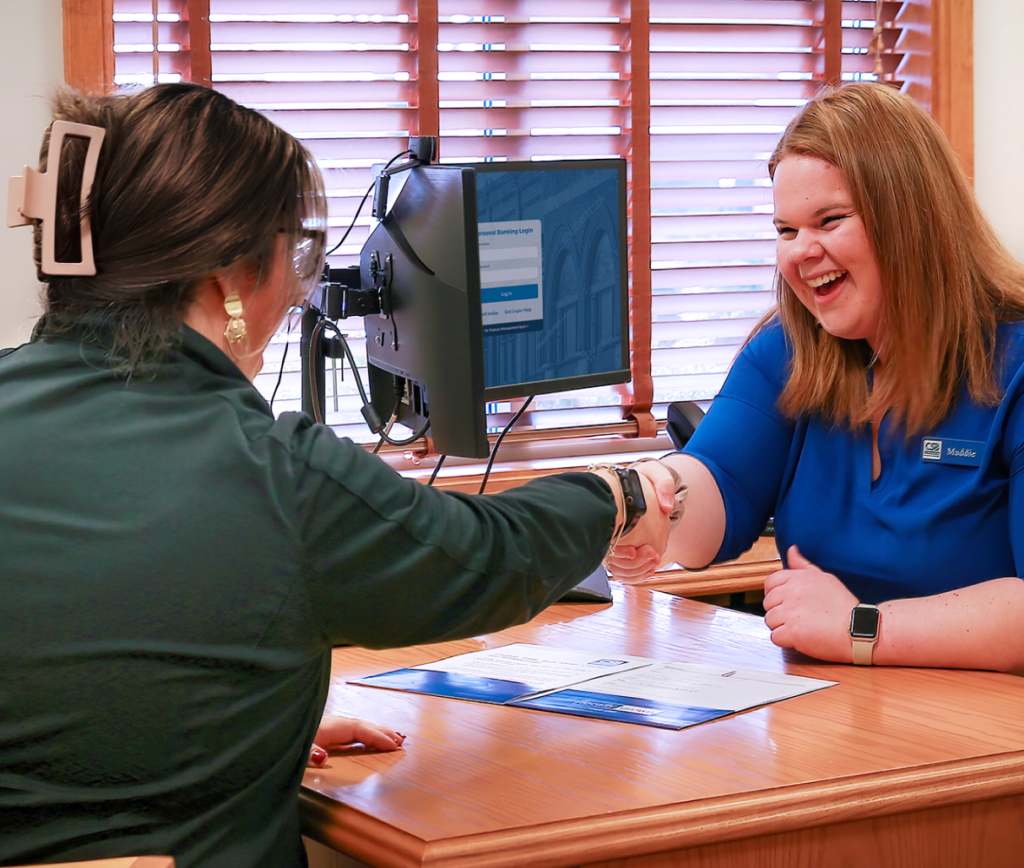 Banker and customer shaking hands over a desk