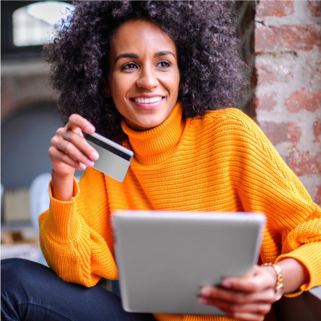 Woman holding a debit/credit card with a tablet smiling