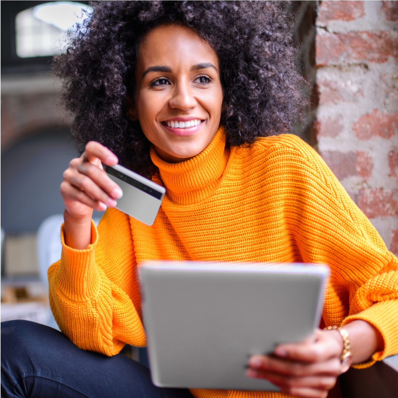 Woman holding a debit/credit card with a tablet smiling