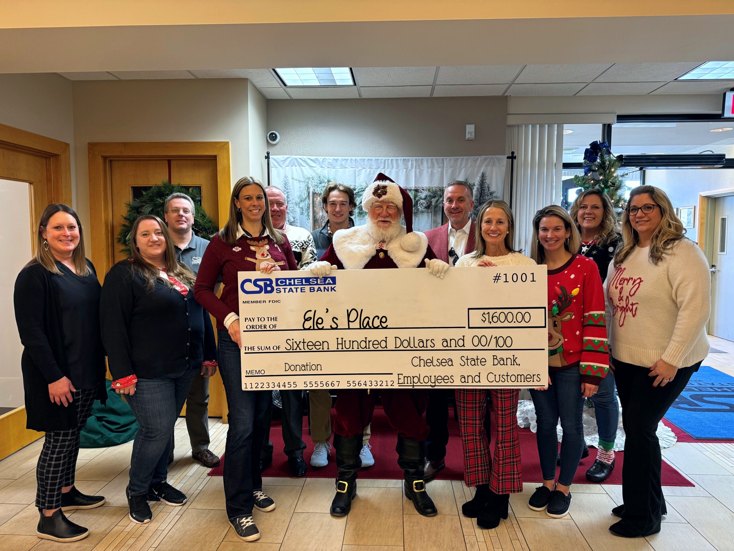 CSB Employees along with Ele's Place Employees and Santa holding a large check for donation to Ele's Place