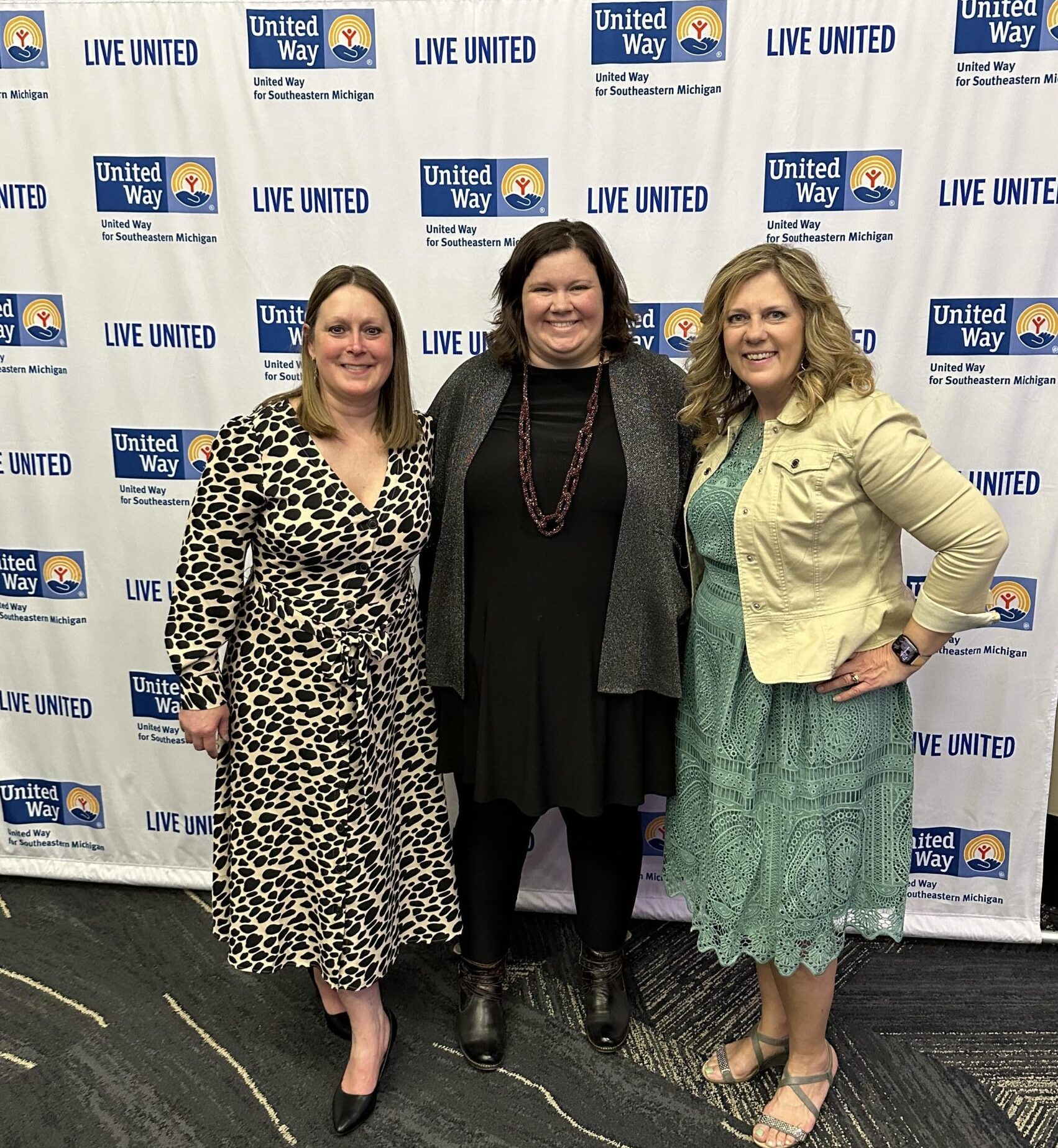 Carie, Emily and Erin standing in front of United Way's Banner at Power of Purse Event